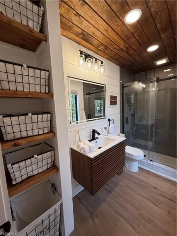 Bathroom featuring vanity, a shower stall, dark wood-style floors, and wooden ceiling