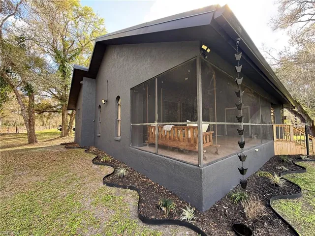 View of property exterior with a sunroom, stucco siding, and a wooden deck