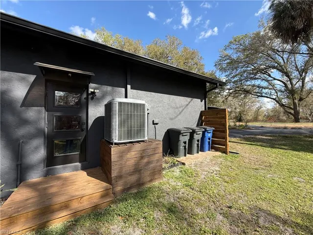 Doorway to property with stucco siding, a deck, and a yard