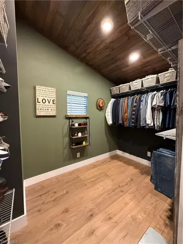 Walk in closet featuring light wood-type flooring and vaulted ceiling