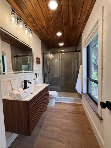 Bathroom with vanity, wood finished floors, a stall shower, wooden ceiling, and recessed lighting