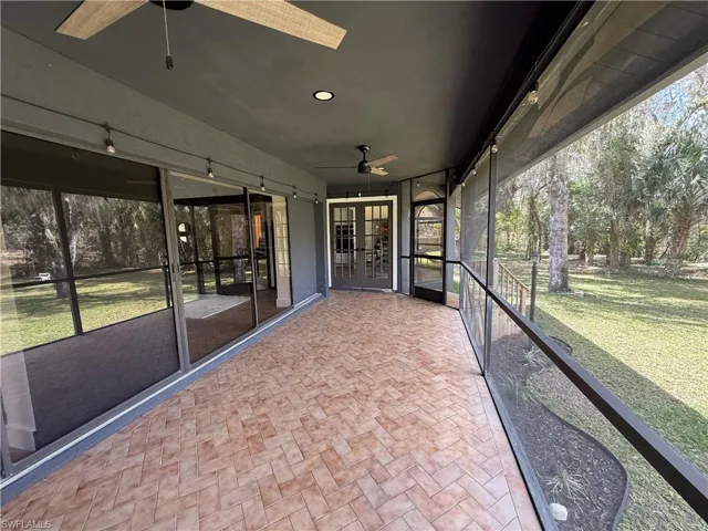 Unfurnished sunroom with a ceiling fan and french doors