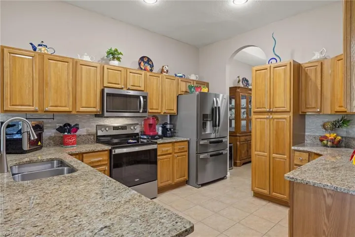 Kitchen with tile backsplash, tile floors, stainless steel appliances