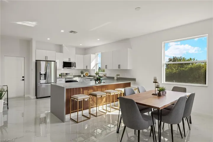 Kitchen featuring a breakfast bar area, white cabinets, kitchen peninsula, and stainless steel appliances