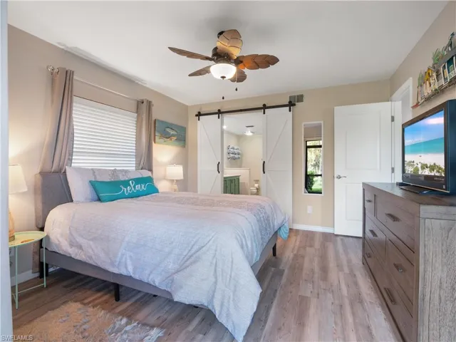 Bedroom featuring baseboards, a barn door, visible vents, and light wood-style flooring