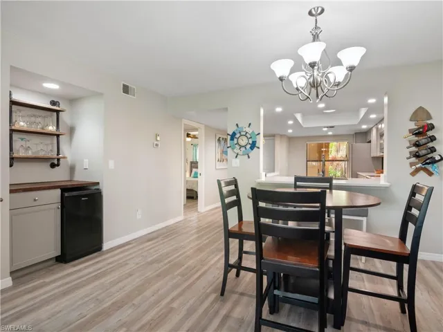Dining room with indoor bar, baseboards, visible vents, and light wood-type flooring