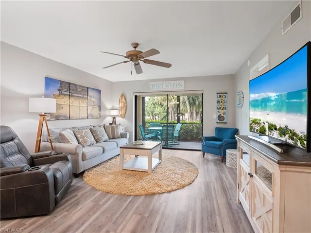 Living room with visible vents, wood finished floors, and ceiling fan