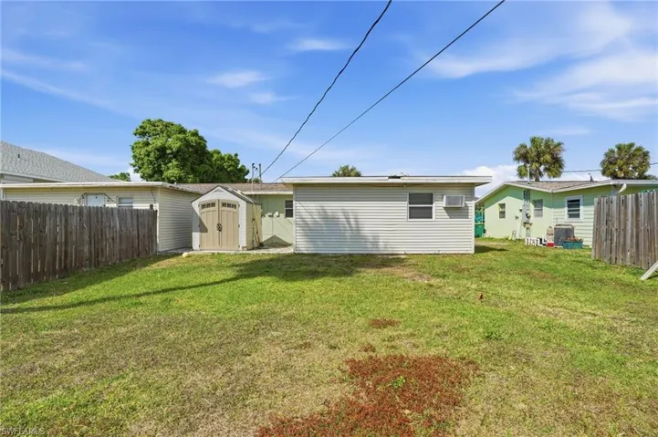 Rear view of property featuring a fenced backyard and a shed