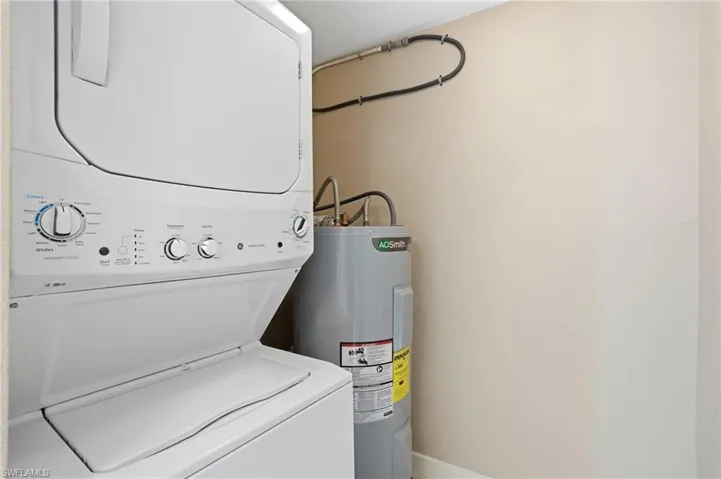 Laundry area with electric water heater and stacked washer and dryer