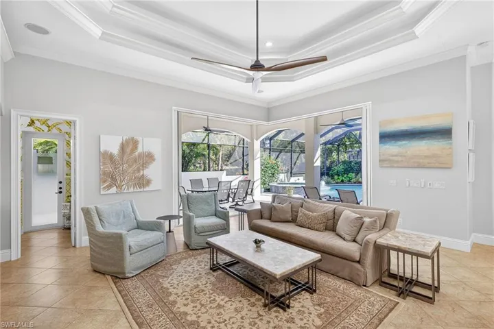 Living area featuring a sunroom, ceiling fan, light tile patterned floors, and ornamental molding