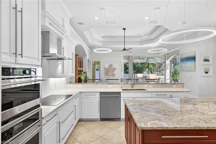 Kitchen featuring light stone countertops, stainless steel appliances, ceiling fan, decorative light fixtures, and two tone cabinetry
