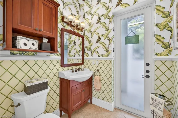 Half bathroom featuring wallpapered walls, vanity, and light tile patterned floors