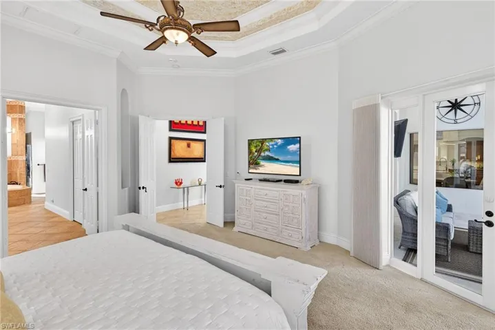 Bedroom with ornamental molding, access to exterior, a raised ceiling, ceiling fan, and light colored carpet