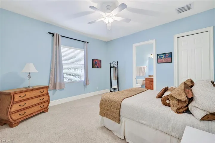 Carpeted bedroom featuring ceiling fan and ensuite bath