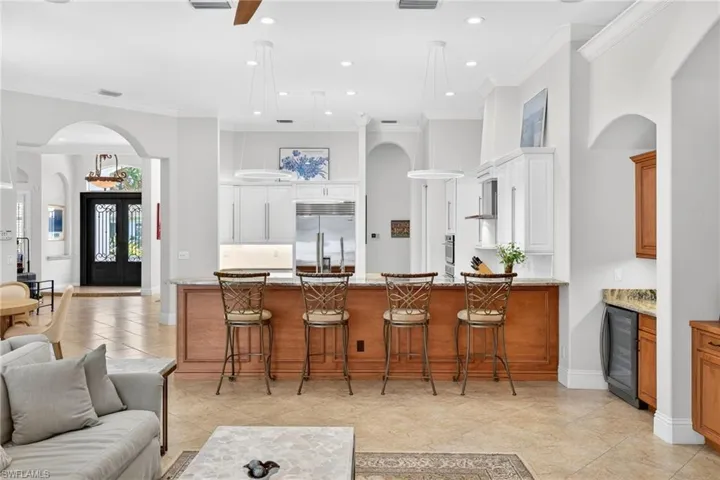 Kitchen with arched walkways, a kitchen bar, ornamental molding, a peninsula, and light stone countertops