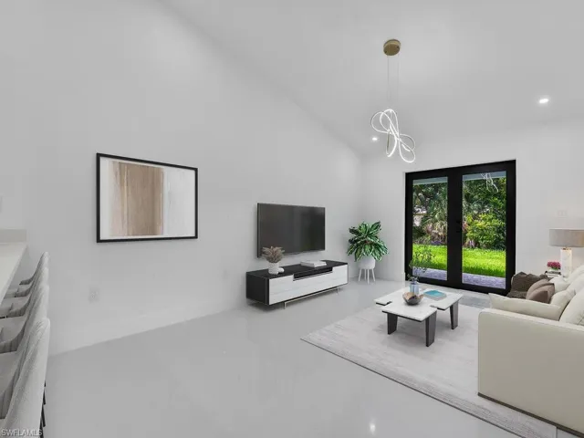 Tiled living room featuring french doors and high vaulted ceiling
