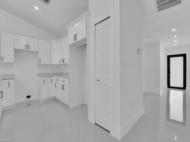 Kitchen with a healthy amount of sunlight, white cabinetry, vaulted ceiling, and light tile patterned floors
