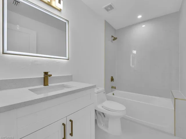 Full bathroom with vanity, tiled shower / bath combo, and toilet