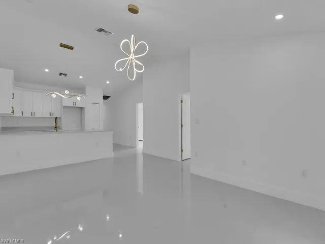Unfurnished living room featuring sink and a chandelier