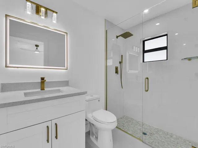 Bathroom with walk in shower, toilet, vanity, ceiling fan, and tile patterned floors