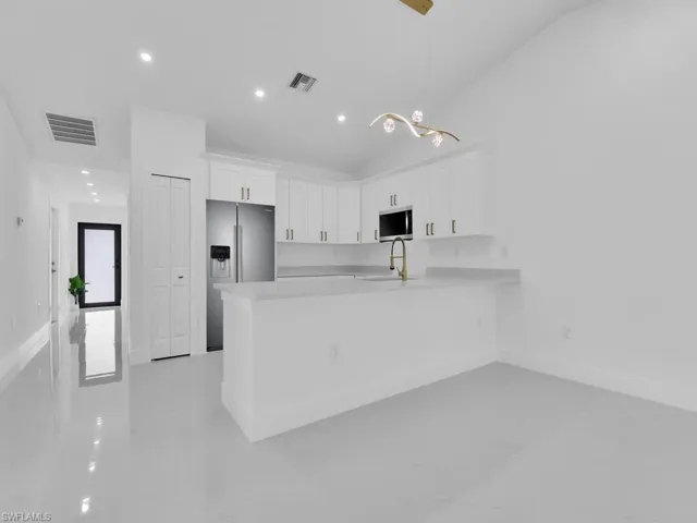 Kitchen featuring white cabinetry, light tile patterned floors, appliances with stainless steel finishes, lofted ceiling, and kitchen peninsula