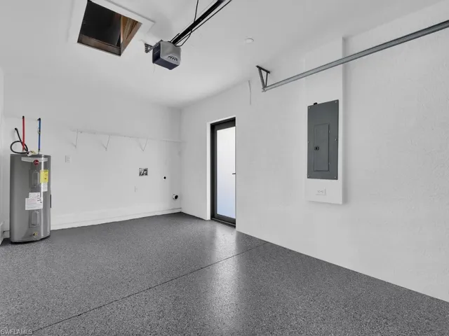 Garage with a garage door opener, water heater, and electric panel