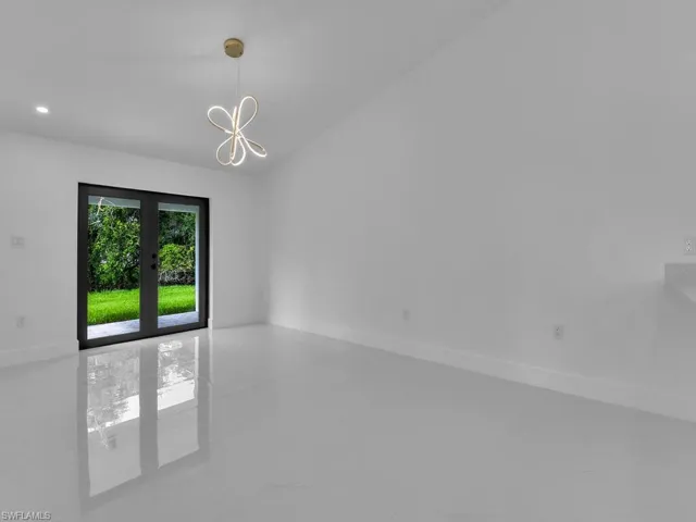 Tiled spare room with french doors and a chandelier