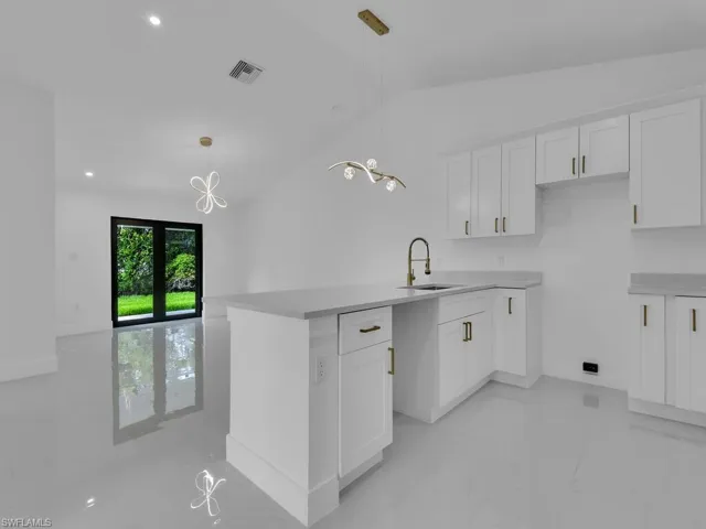 Kitchen featuring light tile patterned floors, decorative light fixtures, vaulted ceiling, and sink