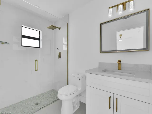 Bathroom featuring vanity, walk in shower, tile patterned flooring, and toilet