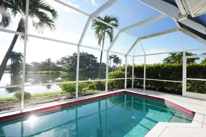 Swimming pool with a water view, a sunroom, and glass enclosure