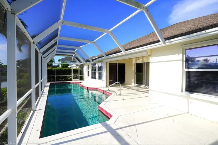 Swimming pool with a sunroom, a patio area, and glass enclosure