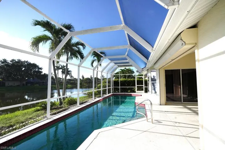 Outdoor pool featuring a sunroom, a water view, a patio, and a lanai