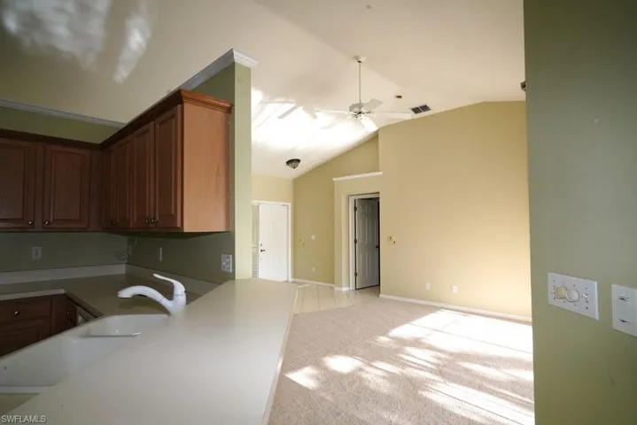 Kitchen featuring light colored carpet, lofted ceiling, light countertops, and a ceiling fan