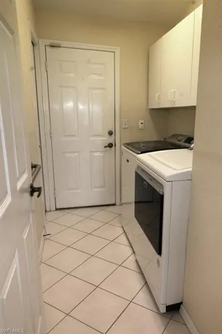 Washroom with light tile patterned floors, cabinet space, and separate washer and dryer