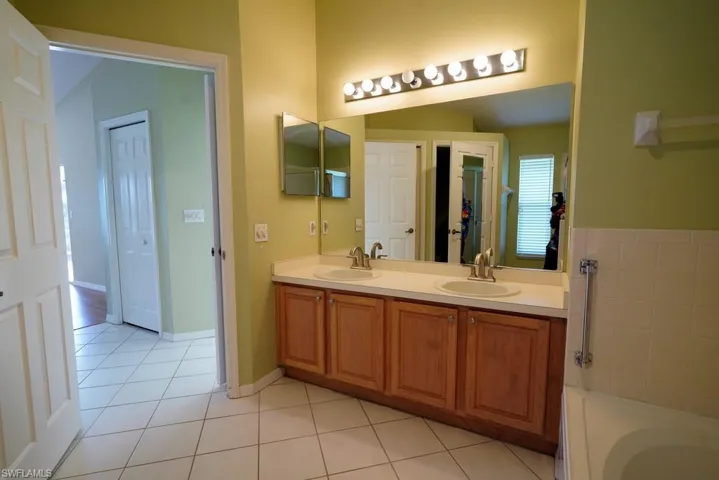 Full bathroom with double vanity, light tile patterned flooring, a garden tub, and a closet
