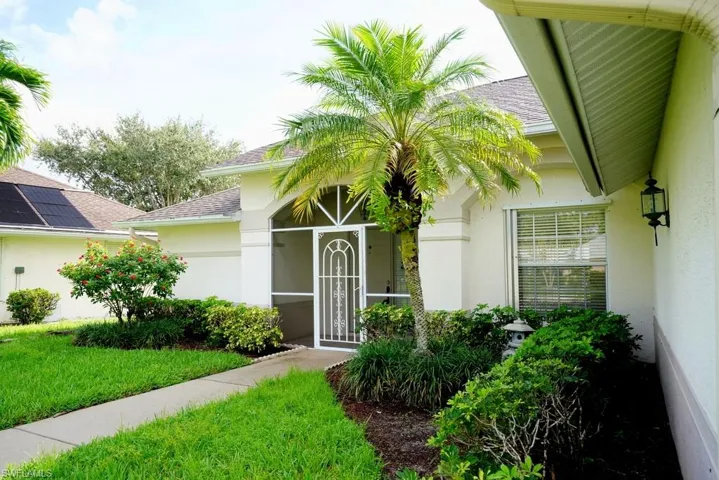 View of exterior entry with a shingled roof, stucco siding, and a lawn