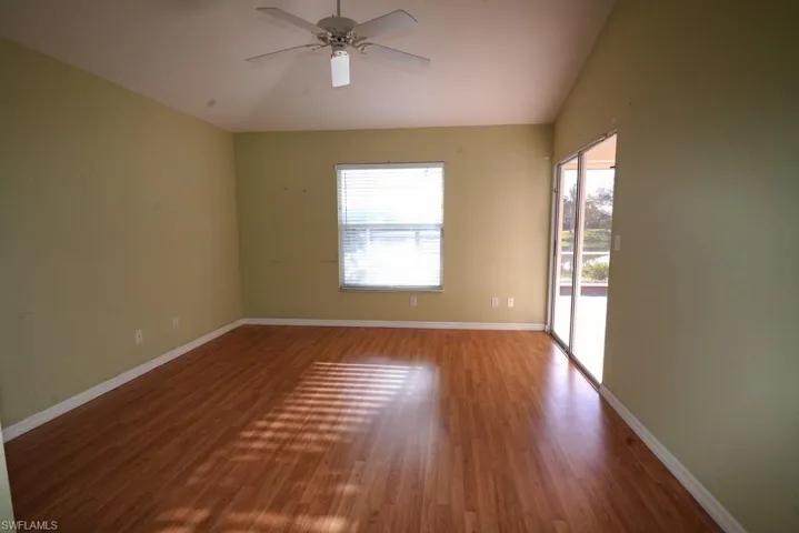 Empty room featuring vaulted ceiling, dark wood finished floors, and a ceiling fan