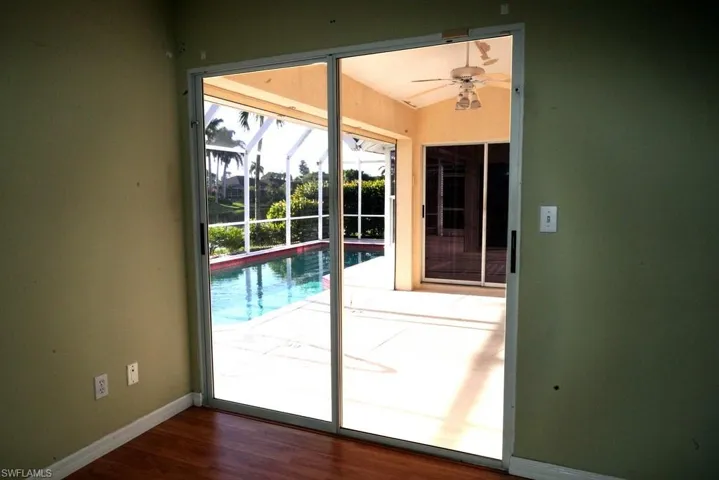 Doorway featuring wood finished floors, a ceiling fan, and a sunroom