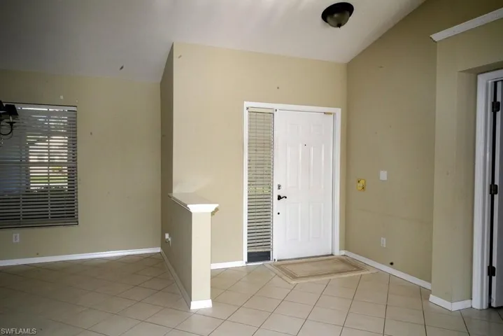 Foyer featuring light tile patterned floors and vaulted ceiling