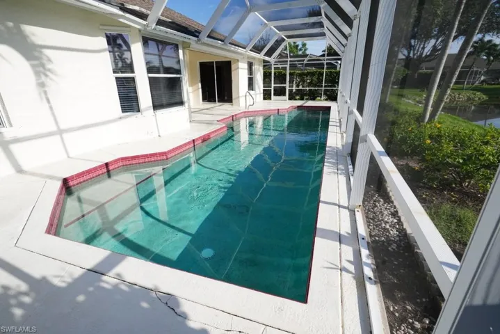 Outdoor pool featuring a sunroom, glass enclosure, and a patio