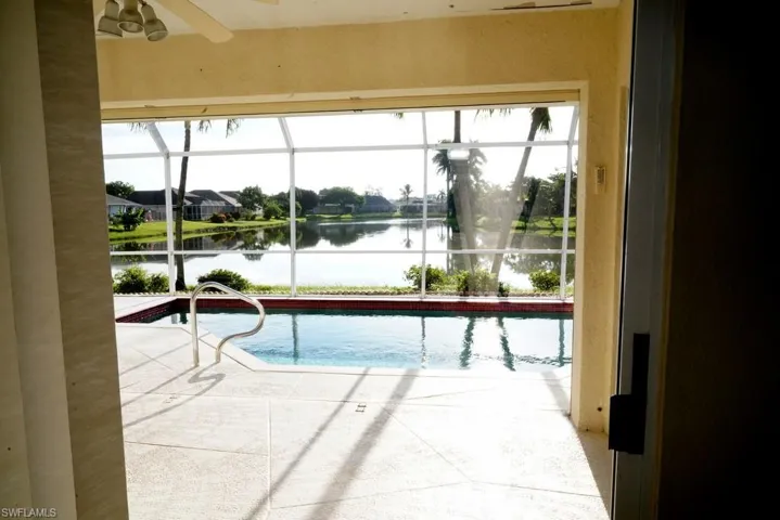 Outdoor pool featuring a water view, a sunroom, and ceiling fan