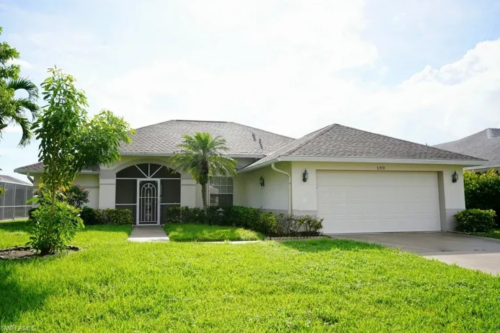 Ranch-style home with driveway, stucco siding, a front yard, a garage, and roof with shingles