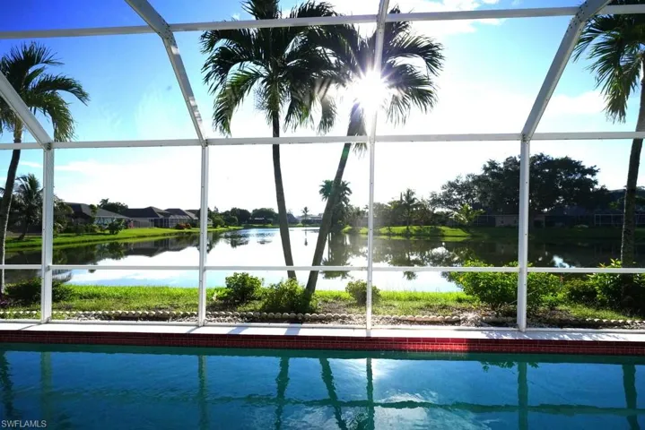 View of swimming pool featuring glass enclosure, a water view, and a sunroom