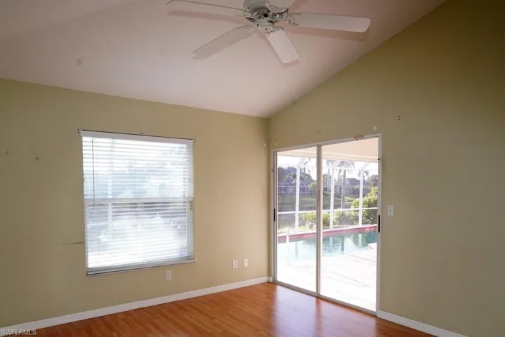Spare room featuring lofted ceiling, wood finished floors, healthy amount of natural light, and ceiling fan