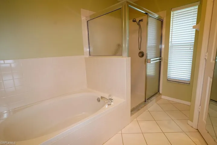 Full bath featuring a shower stall, a bath, and light tile patterned flooring