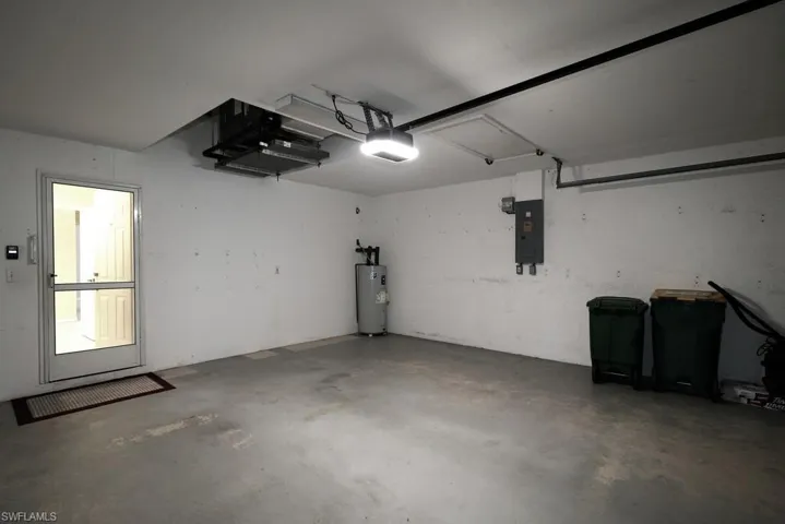 Garage with electric panel, water heater, and a garage door opener