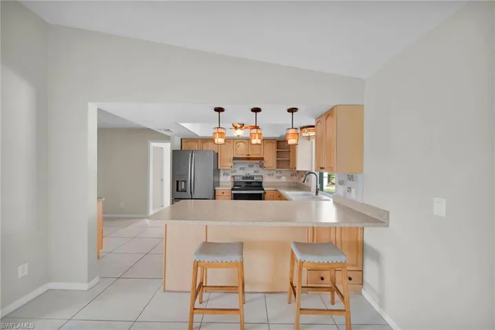 Kitchen with kitchen peninsula, appliances with stainless steel finishes, vaulted ceiling, and sink