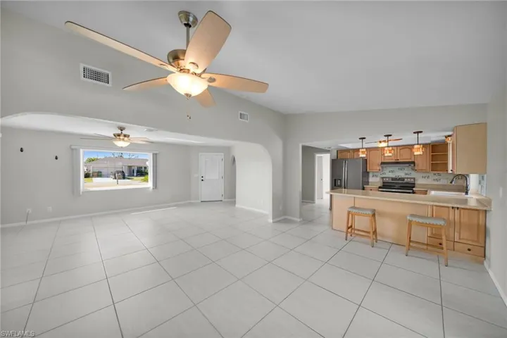 Unfurnished living room with light tile patterned floors, ceiling fan, lofted ceiling, and sink