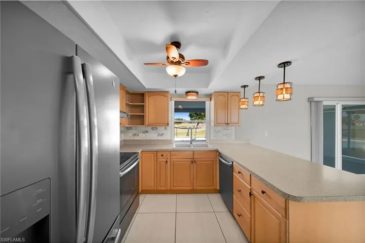 Kitchen with pendant lighting, sink, decorative backsplash, appliances with stainless steel finishes, and kitchen peninsula