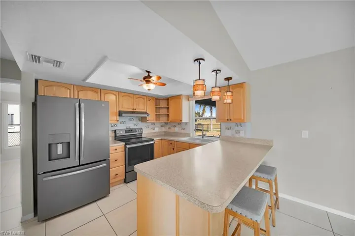 Kitchen with a kitchen breakfast bar, sink, ceiling fan, appliances with stainless steel finishes, and kitchen peninsula